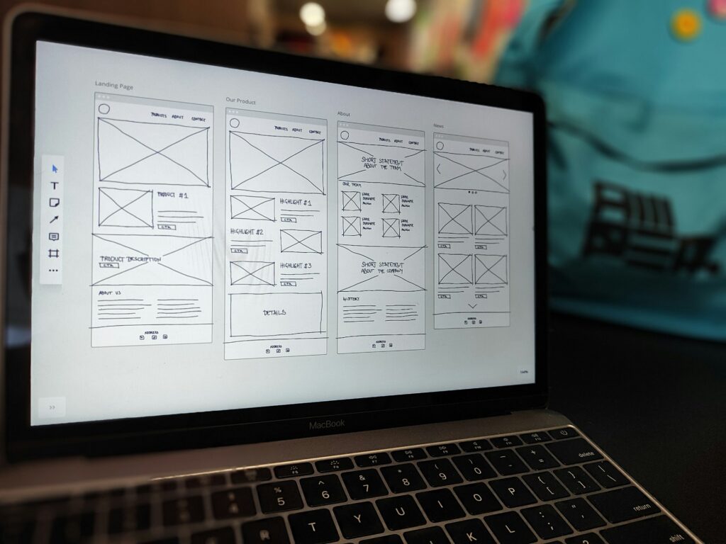 Laptop displaying wireframe website design mockups.